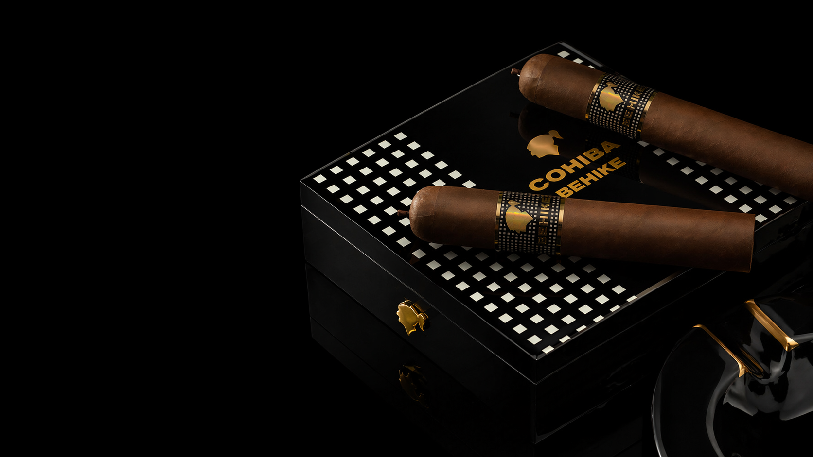A Cohiba Behike box on obsidian, gold checkerboard, mirror reflection